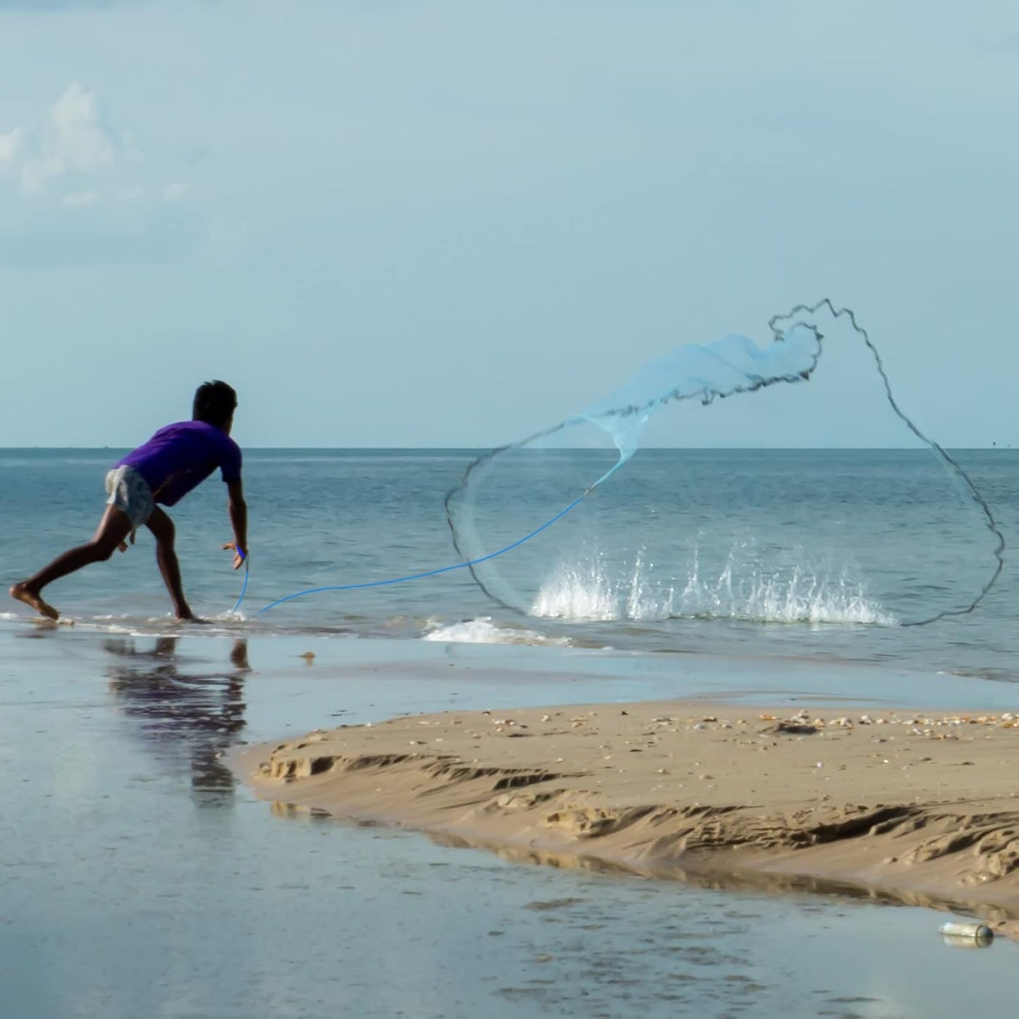 Person casting a Hand Casting fishing net into the ocean on a beach