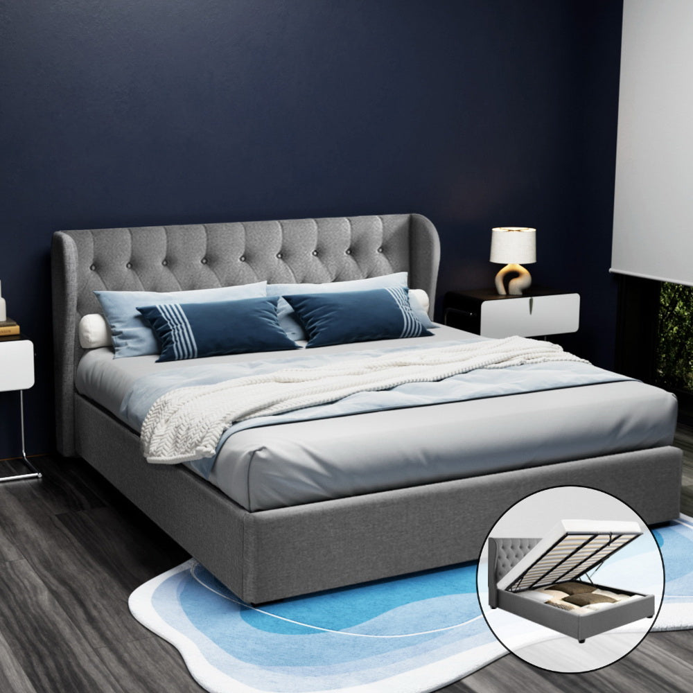 A grey Artiss Issa Bed Frame with fabric upholstery, featuring a tufted headboard and a gas lift storage base, in a room setting with bedding and pillows.