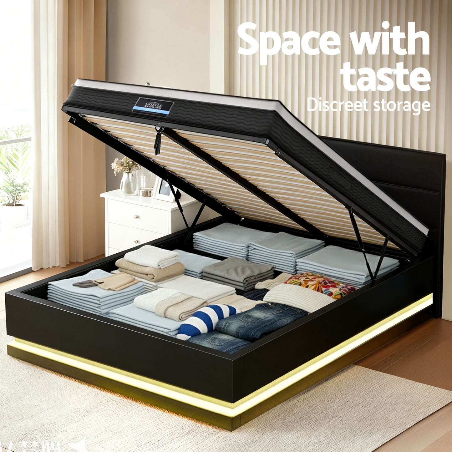 Black bed frame with open storage compartment containing clothes in a room.