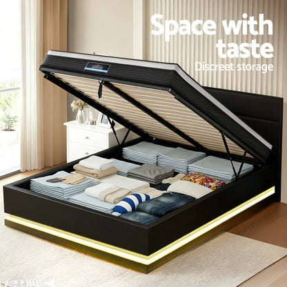 Black bed frame with open storage compartment containing clothes in a room.