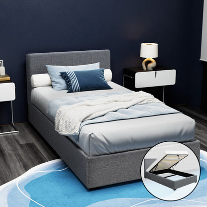 A grey Artiss Nino king single bed frame with faux-linen fabric, padded with foam, and featuring a gas lift storage base. The image shows the bed frame with a mattress, pillows, and a quilt, placed in a room with dark walls and a decorative rug.