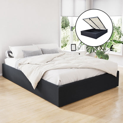 A queen-sized, charcoal-colored gas lift bed frame with a storage compartment underneath, depicted in a room setting with a white bedsheet and pillows on top.