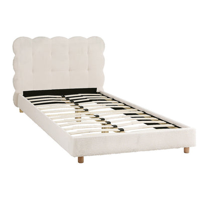 White upholstered bed with scalloped headboard on a white background