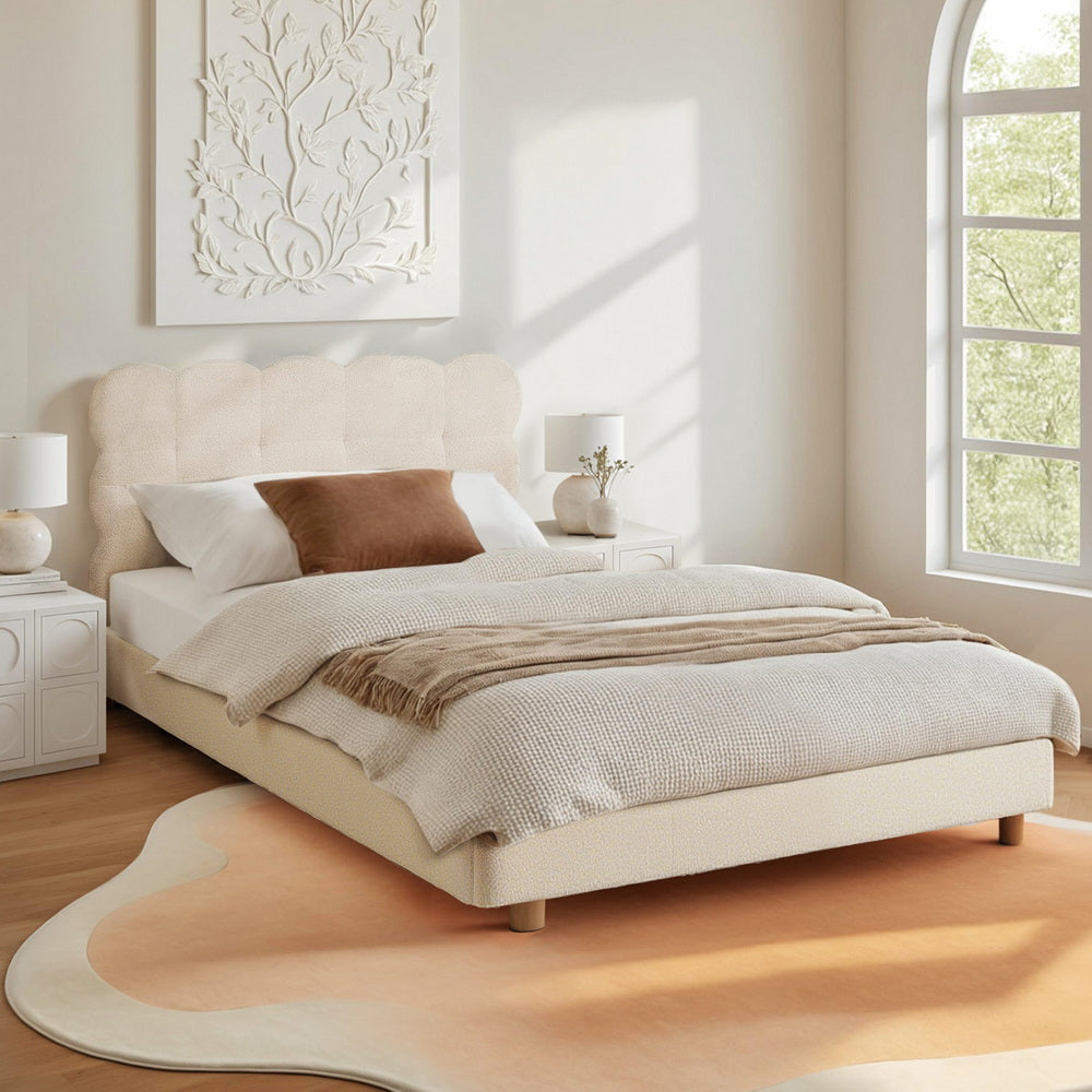 Beige upholstered bed in a bright bedroom with large window