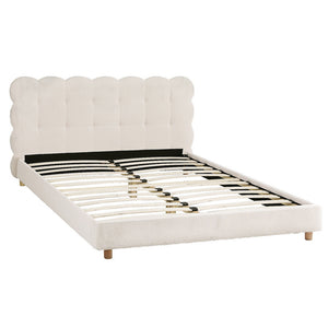 White upholstered bed with scalloped headboard on a white background