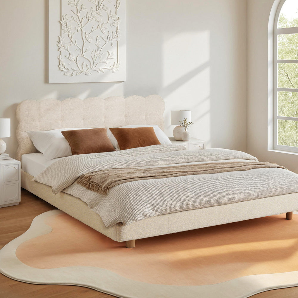 Neatly made bed with beige bedding in a bright bedroom