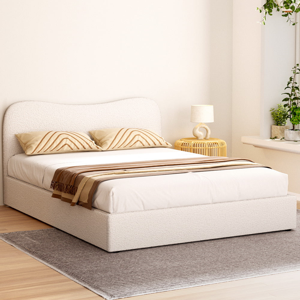 White bed with beige pillows and a blanket in a bedroom setting.