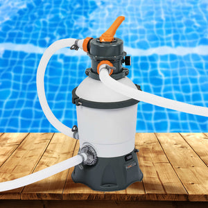 Pool filter pump with hoses on a wooden deck with a pool in the background