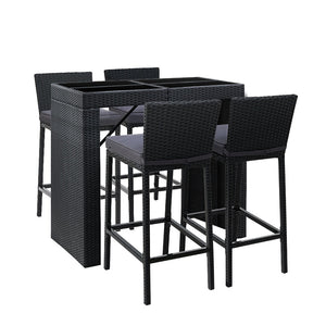 A five-piece outdoor bar set with a rectangular dining table and four matching bar stools, all in black color with a wicker finish. The stools have grey cushions.