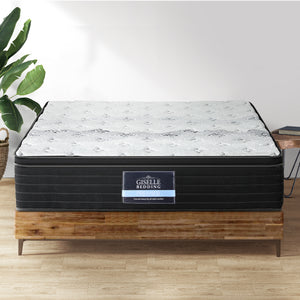 A queen-sized Giselle Bedding Adara series mattress with a super firm structure, displayed on a wooden bed frame, showcasing its knitted fabric cover and pocket spring design.