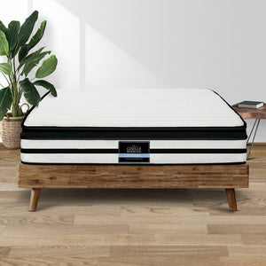 A king-sized Giselle Bedding Euro top mattress on a wooden bed frame, showcasing its white and black striped plush top and side handles.