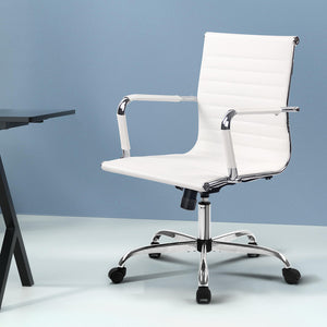 A white, mid-back Artiss gaming office chair with a chrome base and five wheel castors, displayed in a modern interior setting.