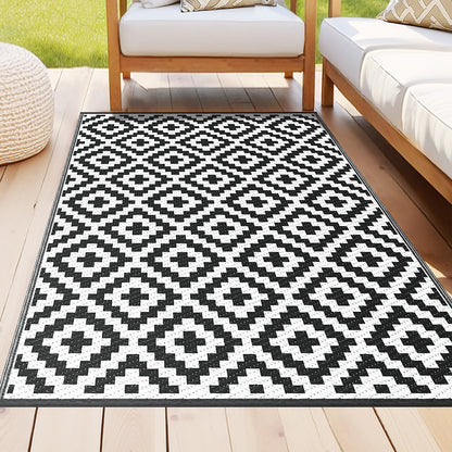 Black and white geometric patterned rug on a wooden floor with outdoor furniture in the background.