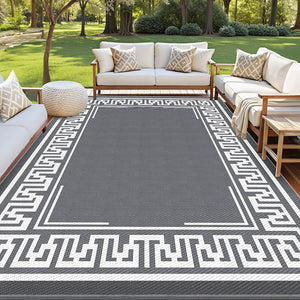 Gray outdoor rug with white patterns in front of a patio set with beige cushions.