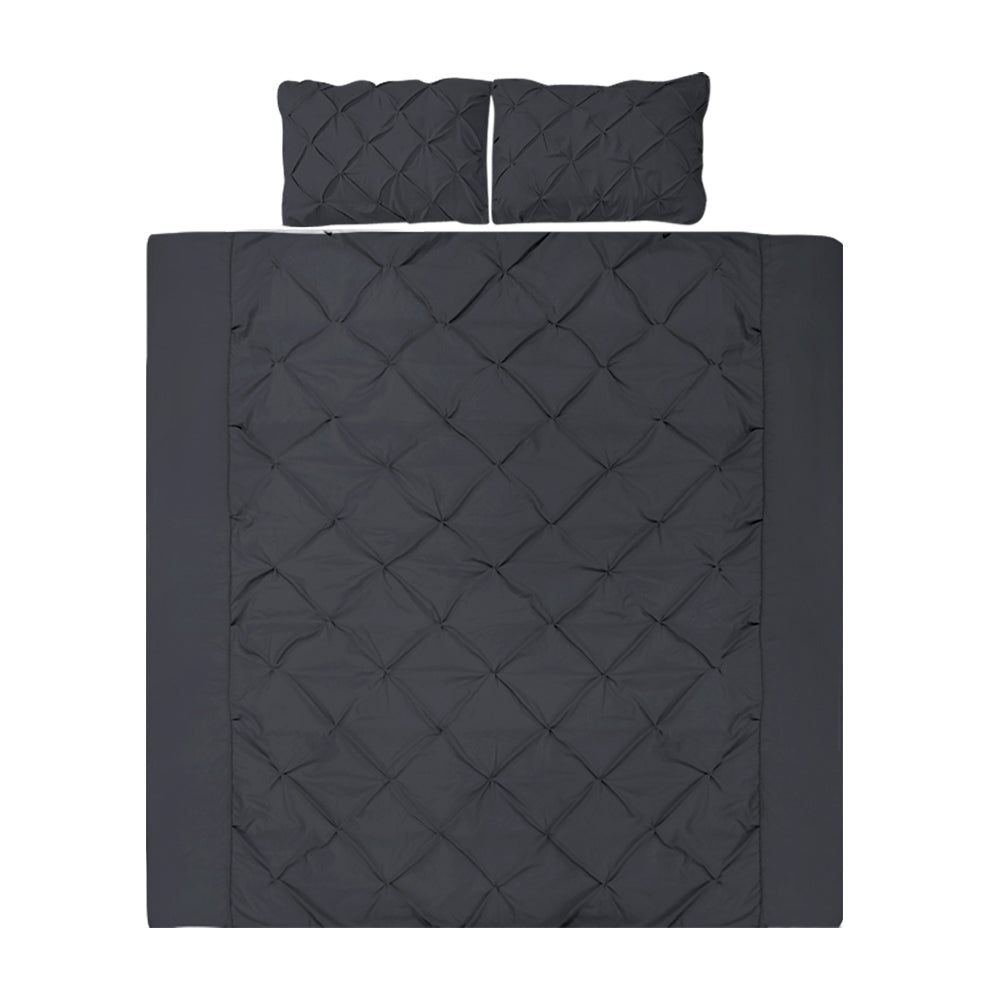 A black quilt cover set with diamond pintuck design, including two pillowcases, displayed on a bed.