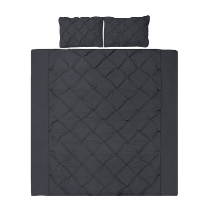 A black quilt cover set with diamond pintuck design, including two pillowcases, displayed on a bed.