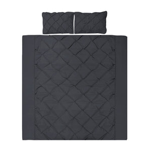 A black quilt cover set with diamond pintuck design, including two pillowcases, displayed on a bed.