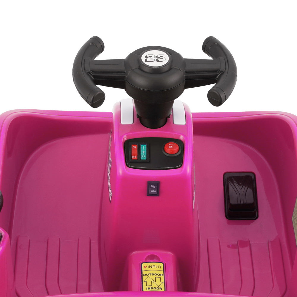 Close-up of a pink toy car with black steering wheel and control panel on a white background