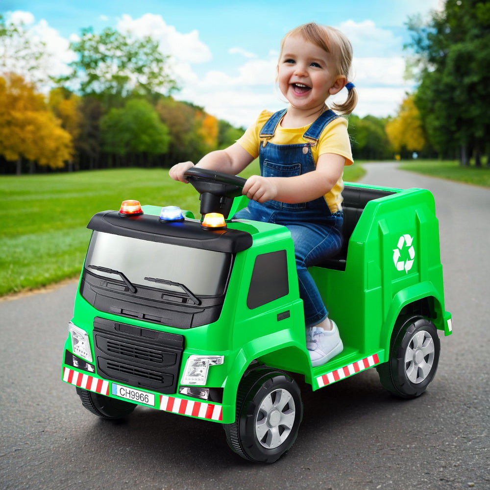 Child playing with a green toy garbage truck in an outdoor setting
