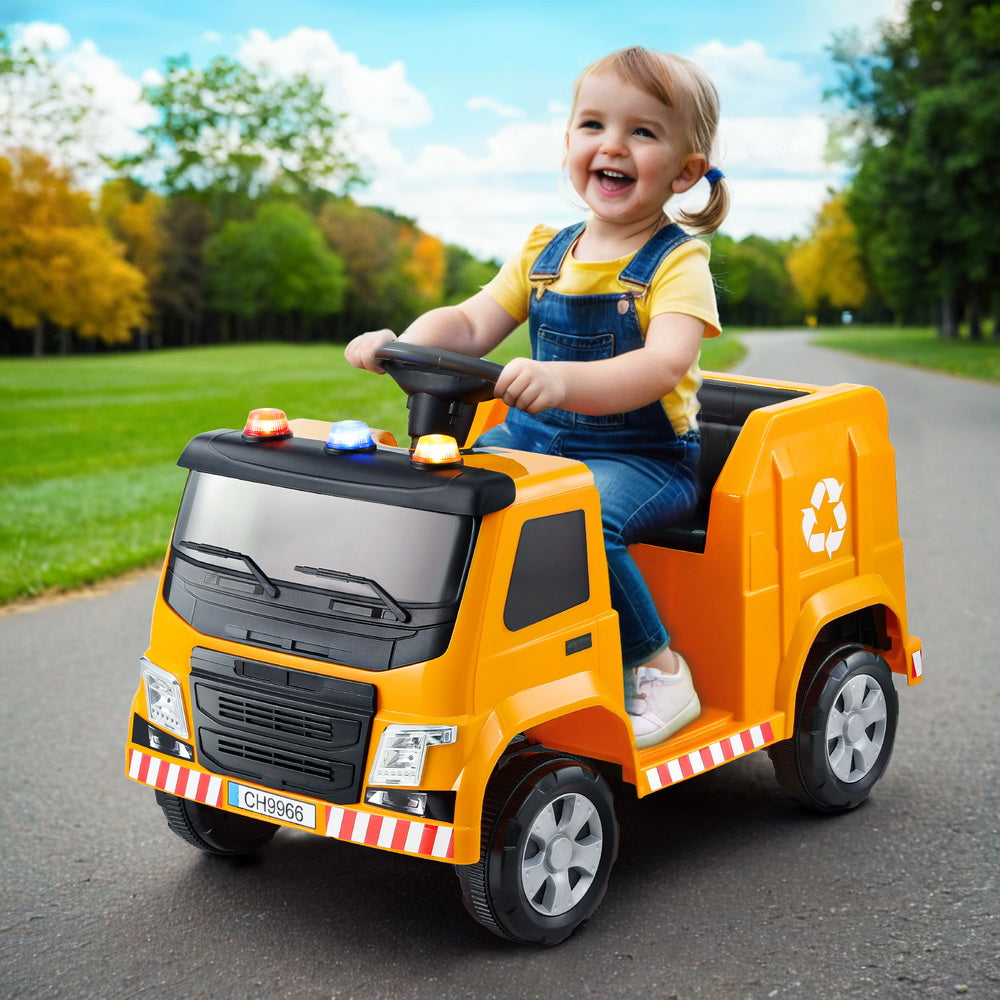 Child playing with a toy garbage truck in a park