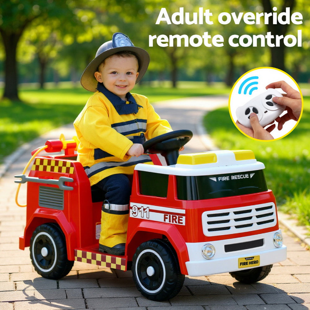 Child in a fire-themed toy truck with remote control feature outdoors.