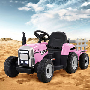 Pink toy tractor with black wheels on a sandy surface under a blue sky.