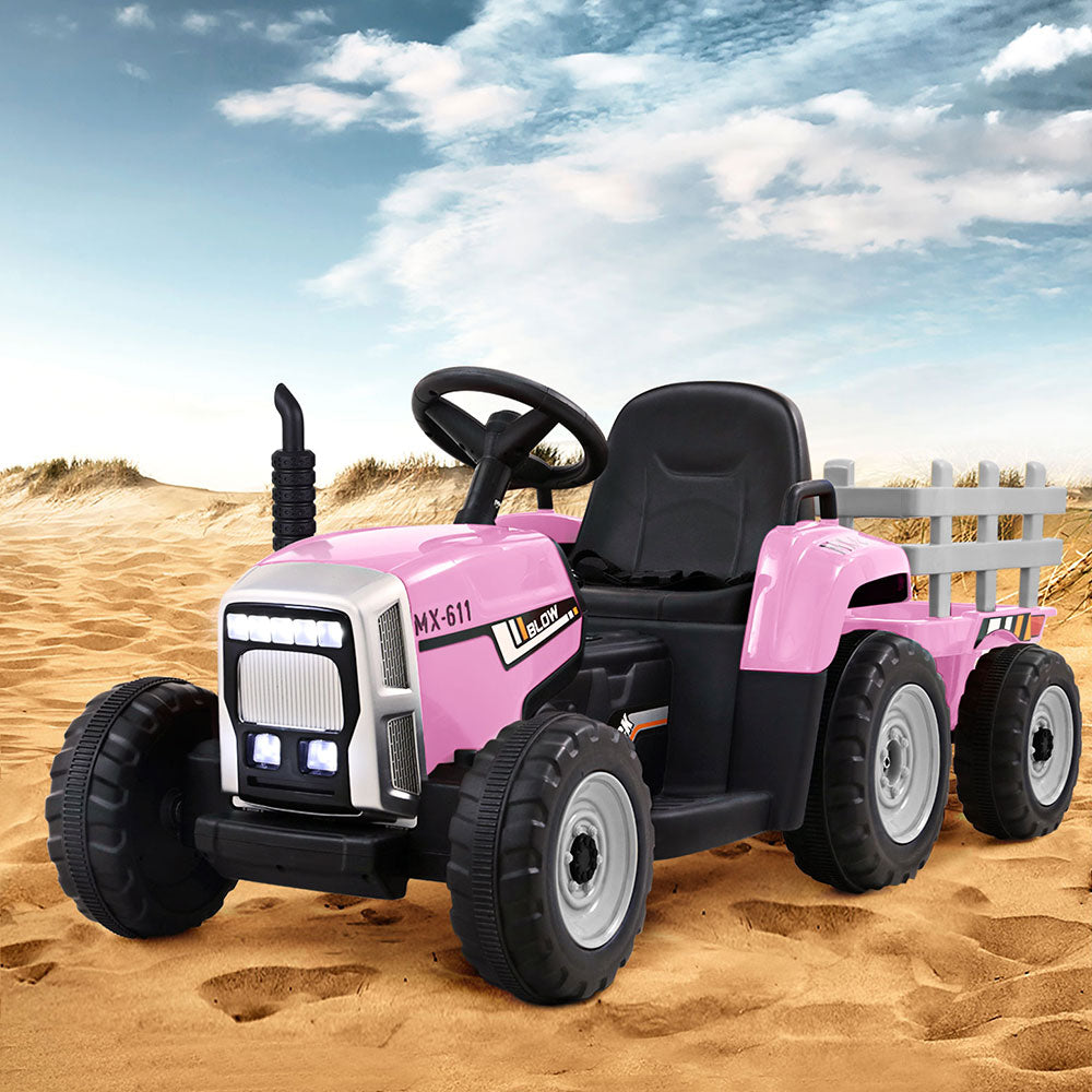 Pink toy tractor with black wheels on a sandy surface under a blue sky.
