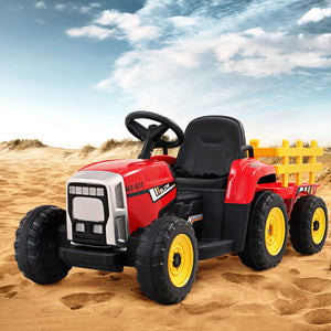 Red toy tractor with a yellow trailer on sandy terrain under a blue sky.