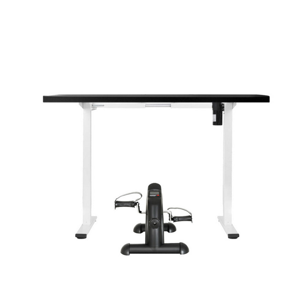Black exercise bike in front of a white desk with a black top