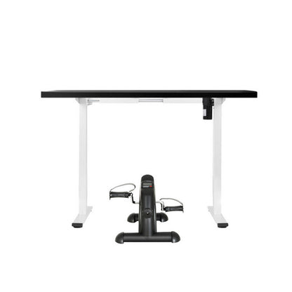 Black exercise bike in front of a white desk with a black top