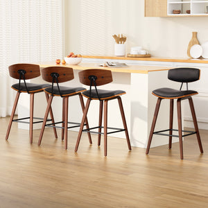 Set of 4 PU Leather Circular Footrest Bar Stools - Black

Wooden Bar Stool
Meticulously crafted with solid wood in a stunning walnut finish for the legs, the Bentwood Bar Stool features a generous puckered faux leather integrated seat and backrest that feel comfortably smooth and look absolutely classy. The mid-height backrest also provides appreciable support while the anti-slip rubber pads at the bottom of the legs remain firm and steady even with robust use. Not least, the powder-coated metal footrest re