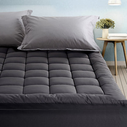 A gray bamboo charcoal microfibre pillowtop mattress topper on a king-sized bed with matching gray pillows, set in a bedroom environment.