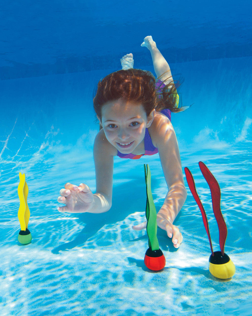 Child swimming underwater with colorful underwater toys in a pool
