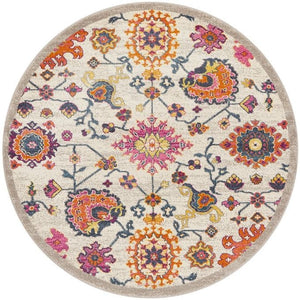 A round multicolored area rug featuring a geometric and floral pattern with prominent pink, orange, and blue colors on a beige background.