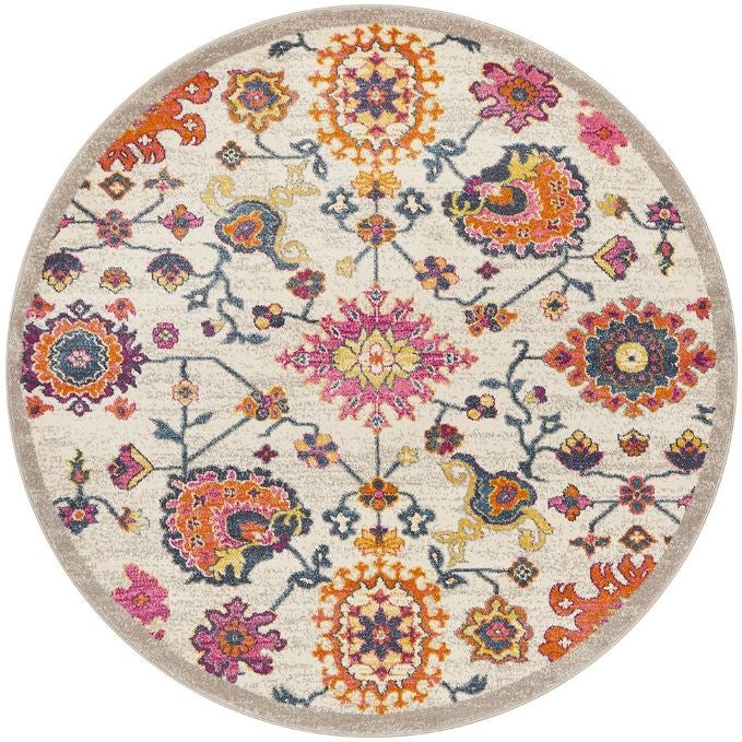 A round multicolored area rug featuring a geometric and floral pattern with prominent pink, orange, and blue colors on a beige background.
