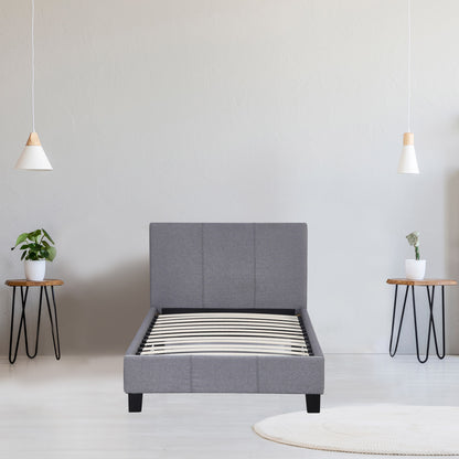 Gray upholstered bed in a minimalistic room with two side tables and plants.