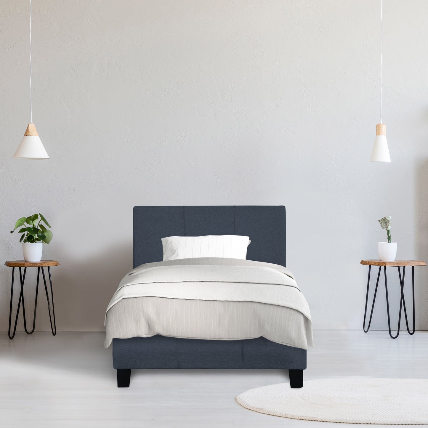 Navy bed frame with white bedding in a minimalistic room with two side tables and lamps.