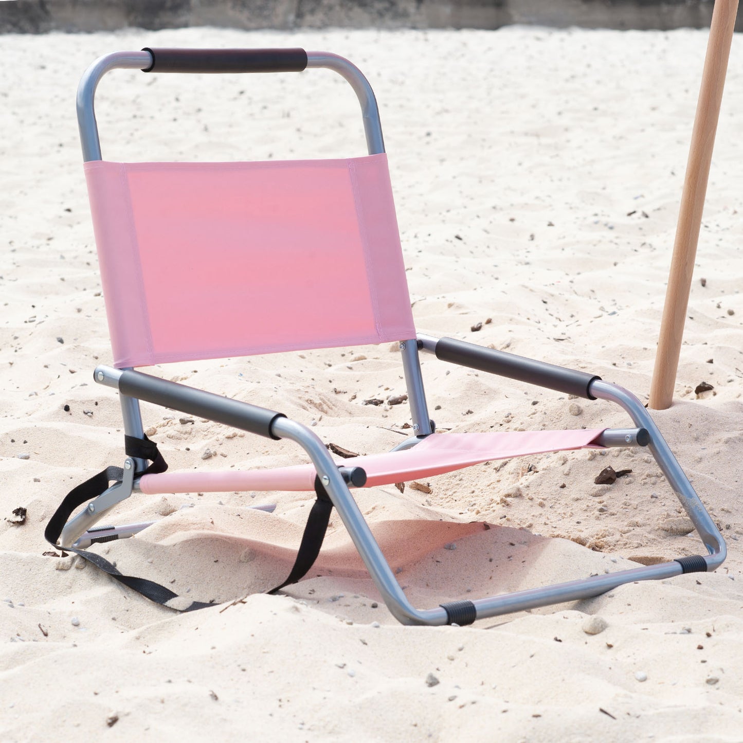 Pink folding chair on a sandy surface