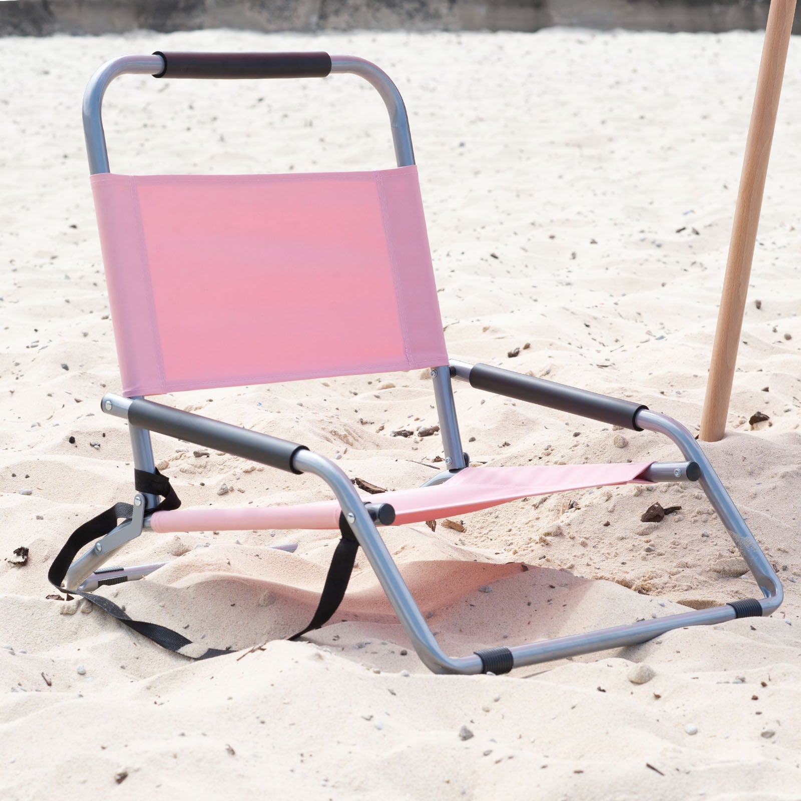 Pink folding chair on a sandy surface