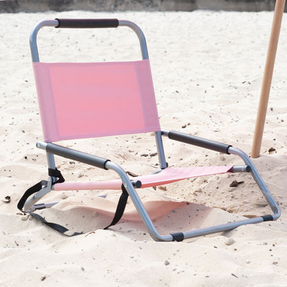 Pink folding chair on a sandy surface