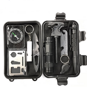 A black survival kit set containing a flashlight, knife, compass, bottle and can opener, tactical pen, and other tools, displayed in an open case.