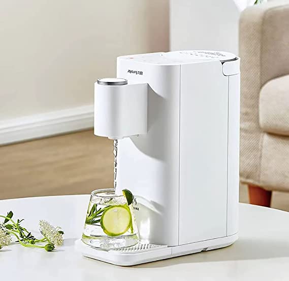 White electric water dispenser pouring water into a glass with lime and mint on a white table.