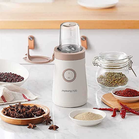 White spice grinder on a kitchen counter with various spices around