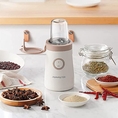 White spice grinder on a kitchen counter with various spices around
