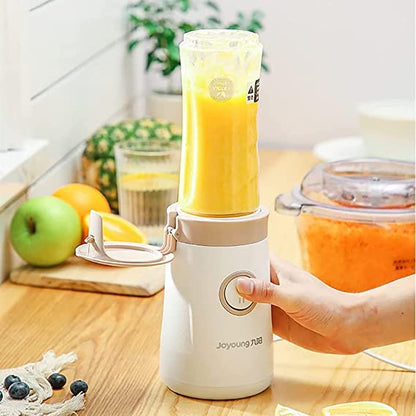 Hand holding a portable blender with a yellow smoothie on a kitchen counter.
