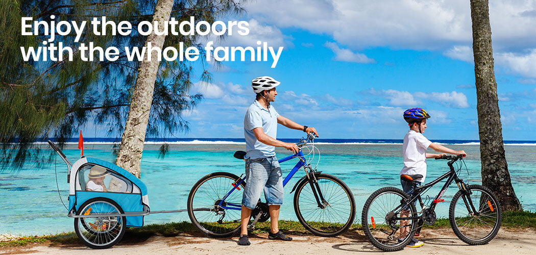 Man and child with bicycles and a trailer by a beach