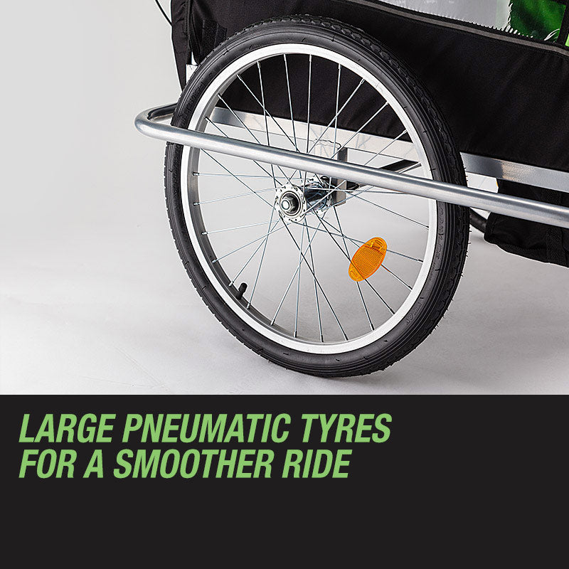 Close-up of a bicycle trailer wheel with large pneumatic tyres on a gray background.