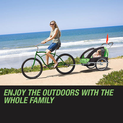 Woman riding a green bicycle with a child in a trailer on a beach.