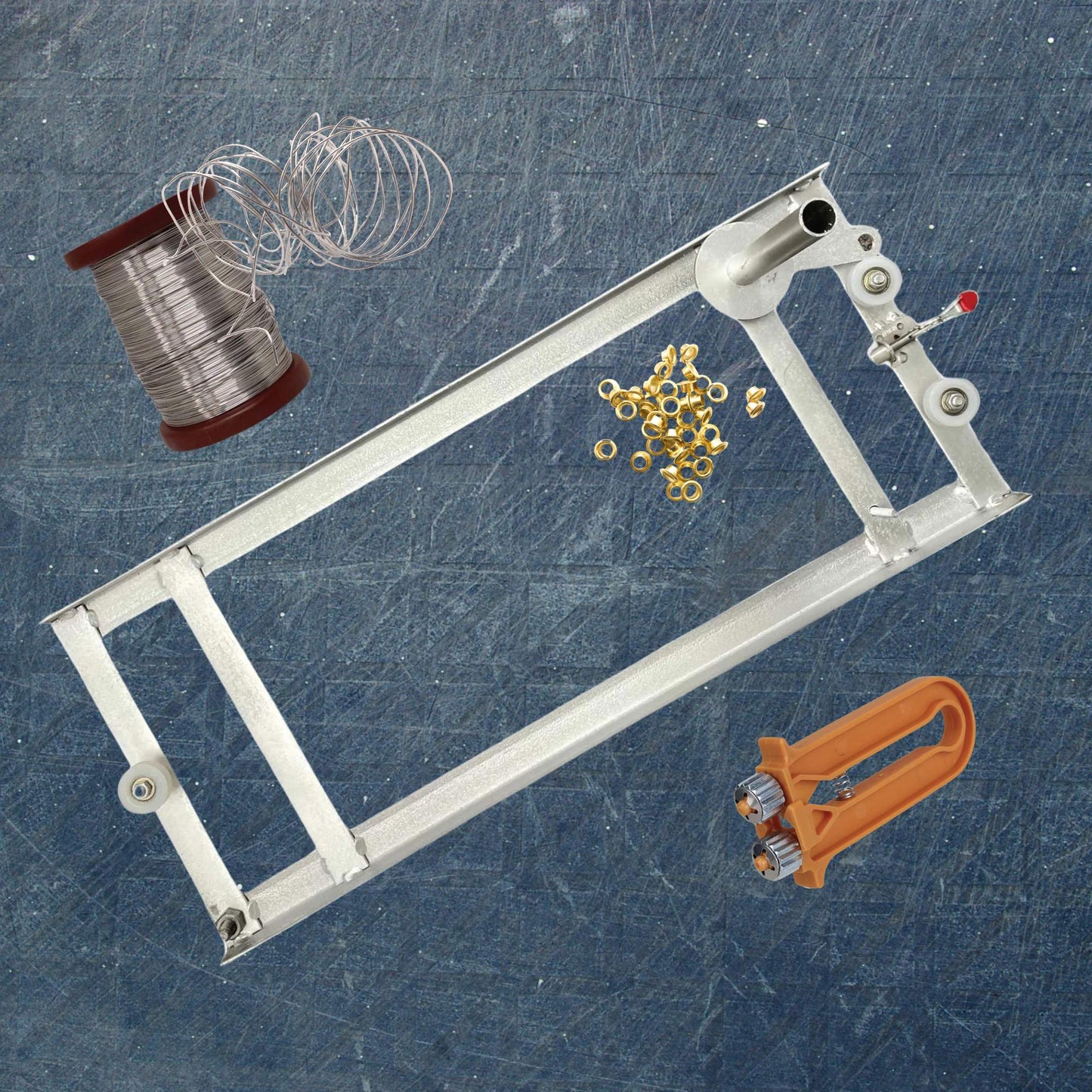 Metal frame with spool of wire, gold beads, and orange tool on a textured blue background