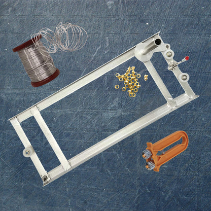 Metal frame with spool of wire, gold beads, and orange tool on a textured blue background